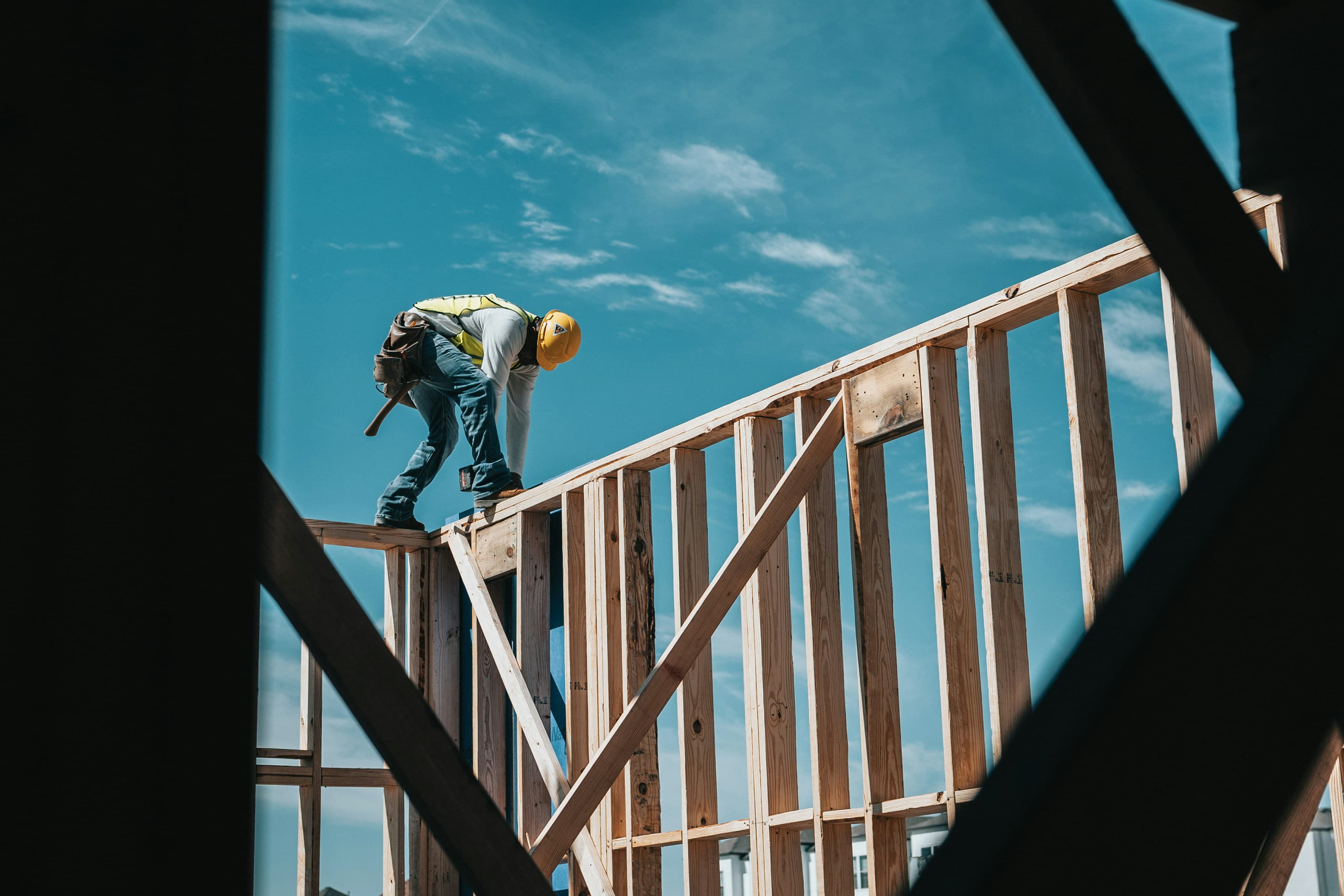 Framer working on a residential stud wall against open sky